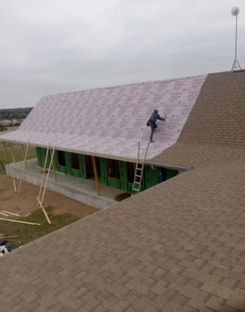 Worker preparing underlayment for a metal roof installation in Bloomfield